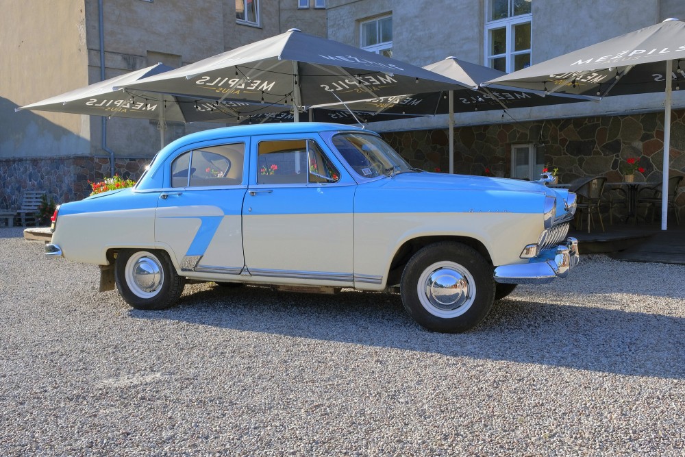 Blue and white vintage car GAZ-21 Volga parked near outdoor cafe