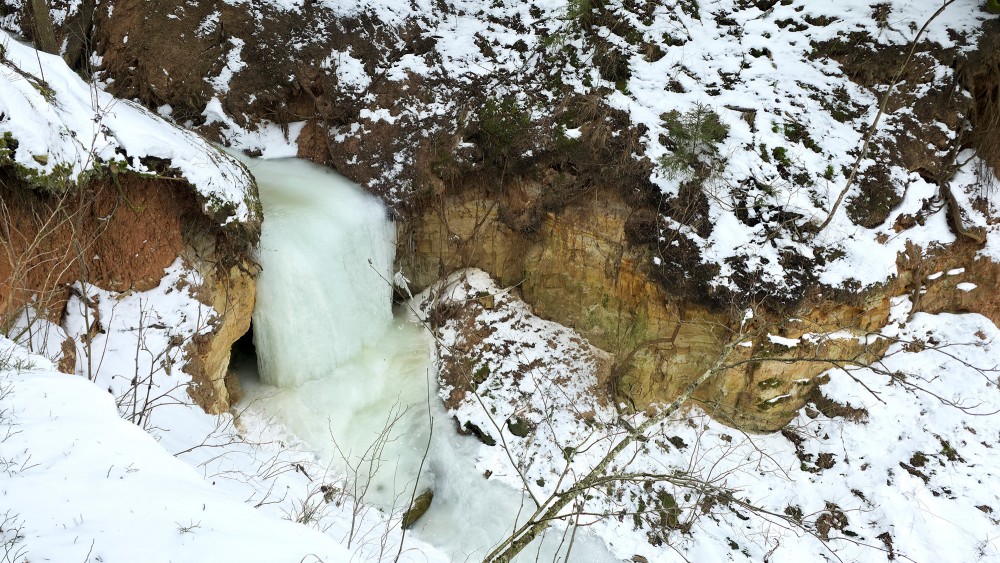 Winter landscape with the frozen Omiķi ravine waterfall