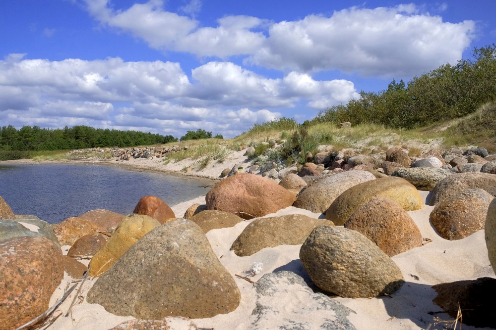 Akmeņaina piekraste ar smiltīm, kāpām un mierīgu ūdeni
