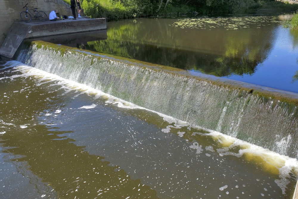 Akmena River Weir with Cascading Water and Water Lilies