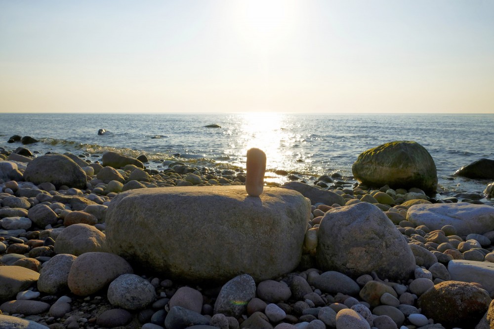 Akmeņu kompozīcija jūrmalā saulrieta gaismā