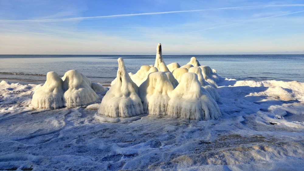 Ice-covered pier on Staldzene beach in winter by the Baltic Sea