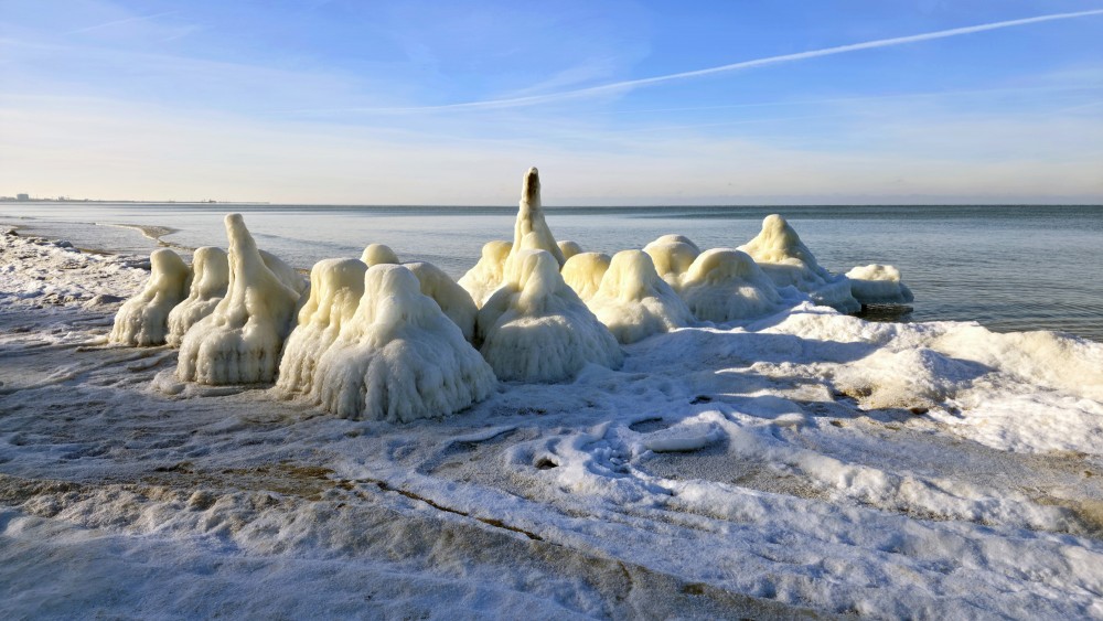 Ice-covered pier on Staldzene beach on a sunny winter day