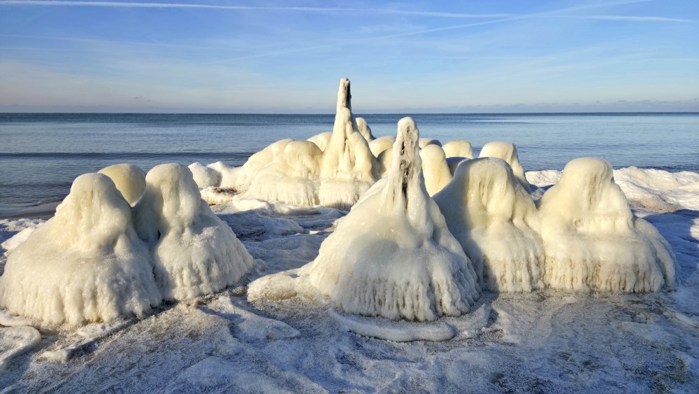 Ice-covered coastal poles at Staldzene beach by the calm Baltic Sea in winter