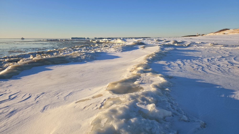 Snowdrifts and ice piles on Pape beach on a sunny winter day