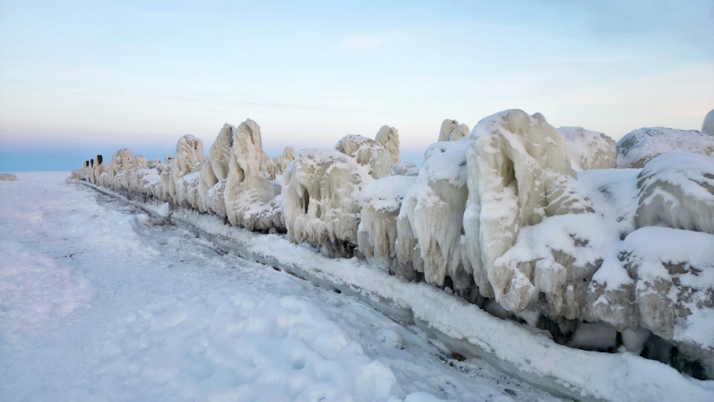 Heavily iced Engure breakwater in winter twilight