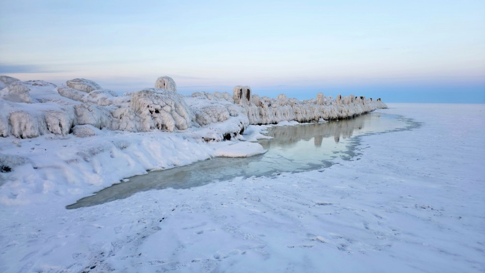 Winter shore landscape with the icy Engure breakwater