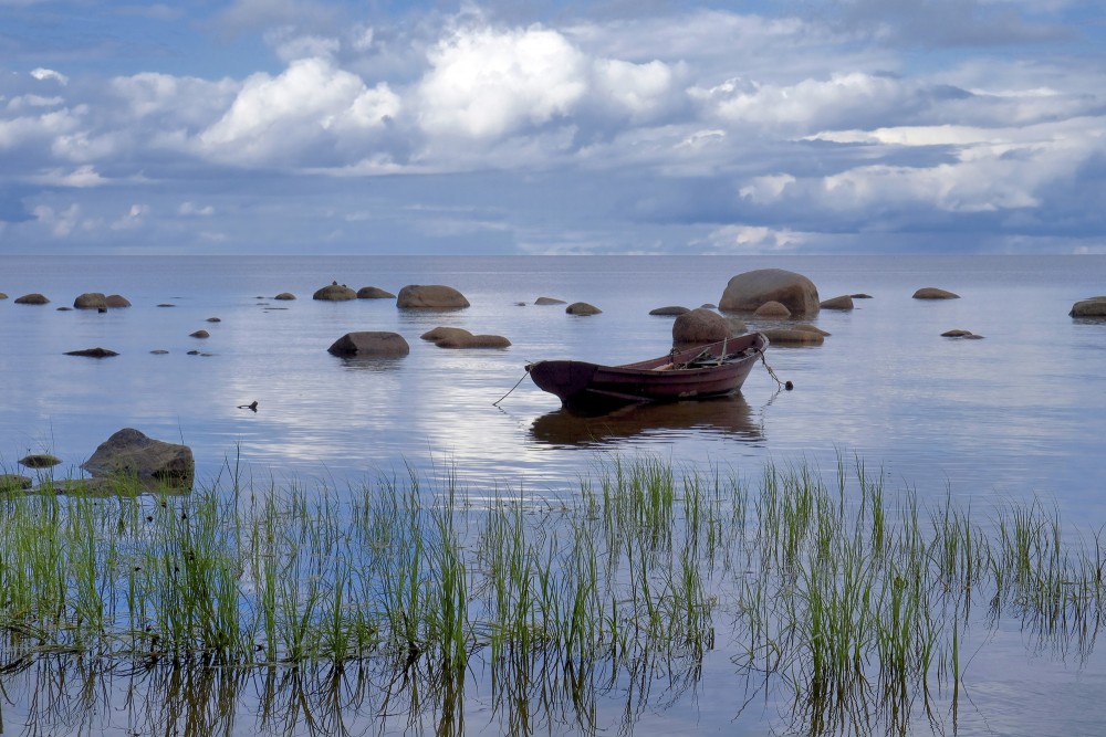 Akmeņainā jūrmala un laiva Akmeņainā jūrmala un laiva