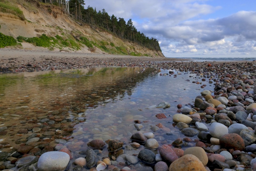 Sārnates stāvkrasts, Akmeņaina pludmale pie stāvkrasta ar mierīgu ūdens atspulgu
