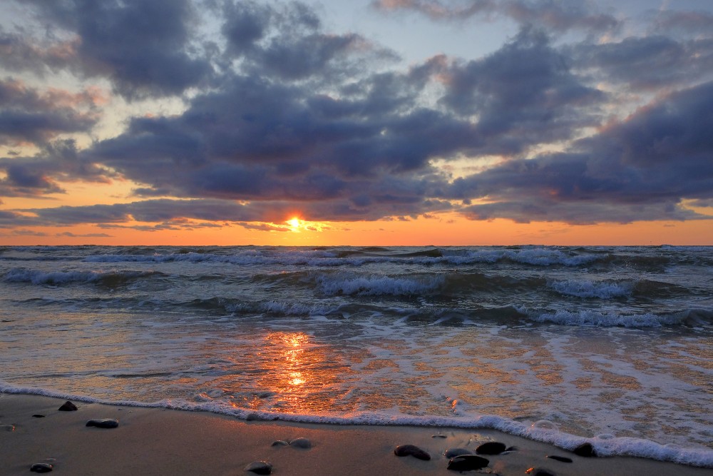 Saulriets Baltijas jūrā, mākoņainas debesi