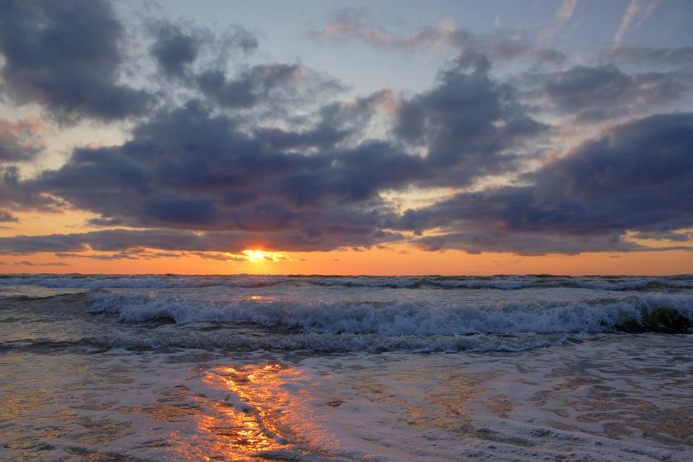 Saulriets Baltijas jūrā, mākoņainas debesi