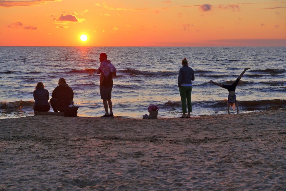 Cilvēki vēro saulrietu jūrā