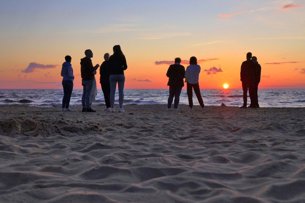 Cilvēki vēro saulrietu jūrā