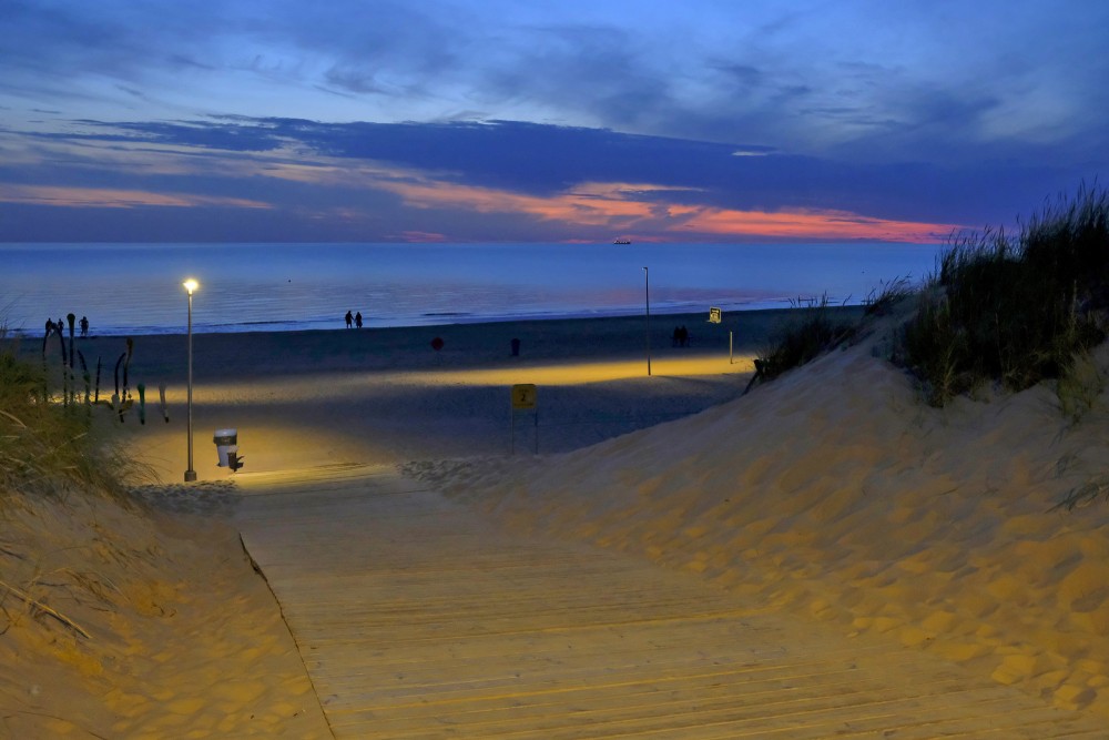 Saulrieta gaisotne Ventspils pludmalē ar laipu cauri kāpām