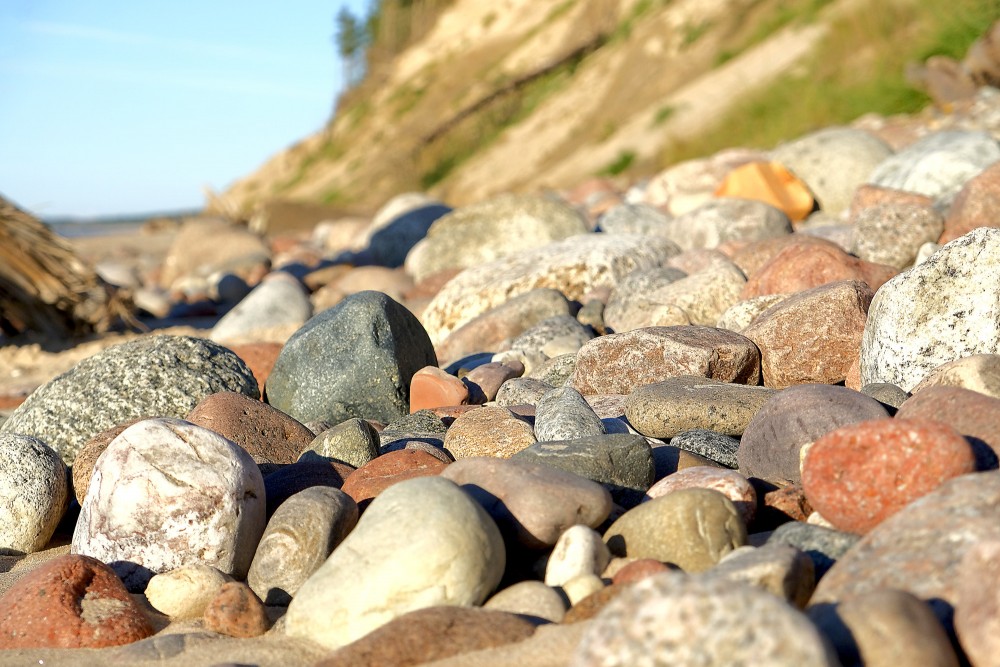 Large pebbles on a sandy beach with a steep bank in the background Large pebbles on a sandy beach with a steep bank in the background