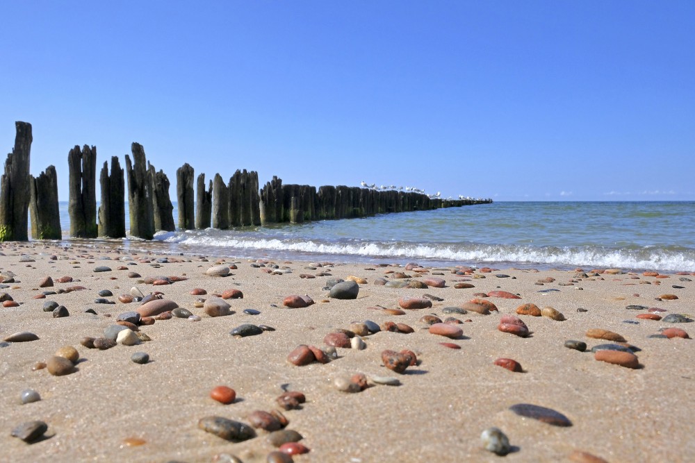 Nidas pludmale ar oļiem un koka molu jūrā