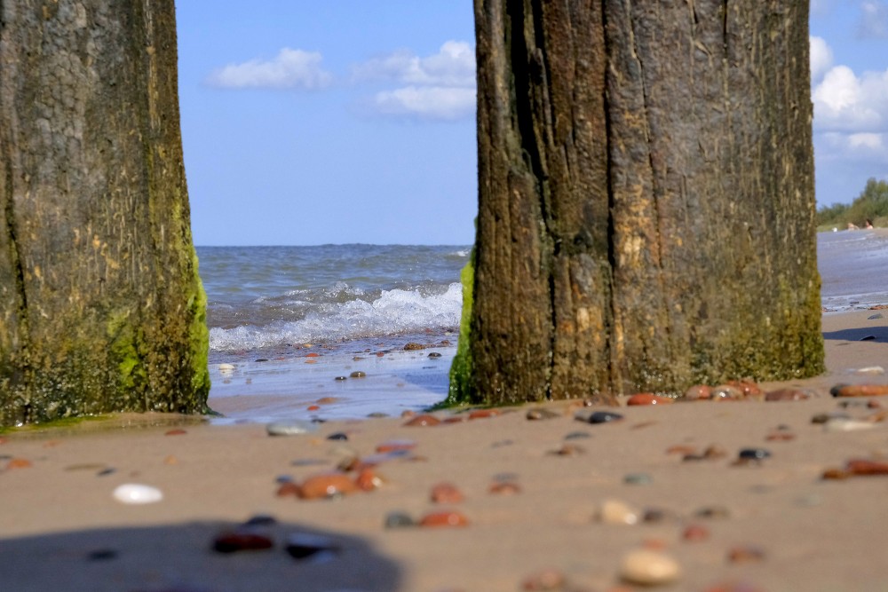 Skats starp koka pāļiem uz jūru un pludmali