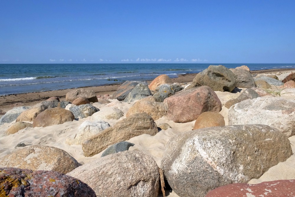 Akmeņaina Papes pludmale ar smiltīm un lēzeniem viļņiem