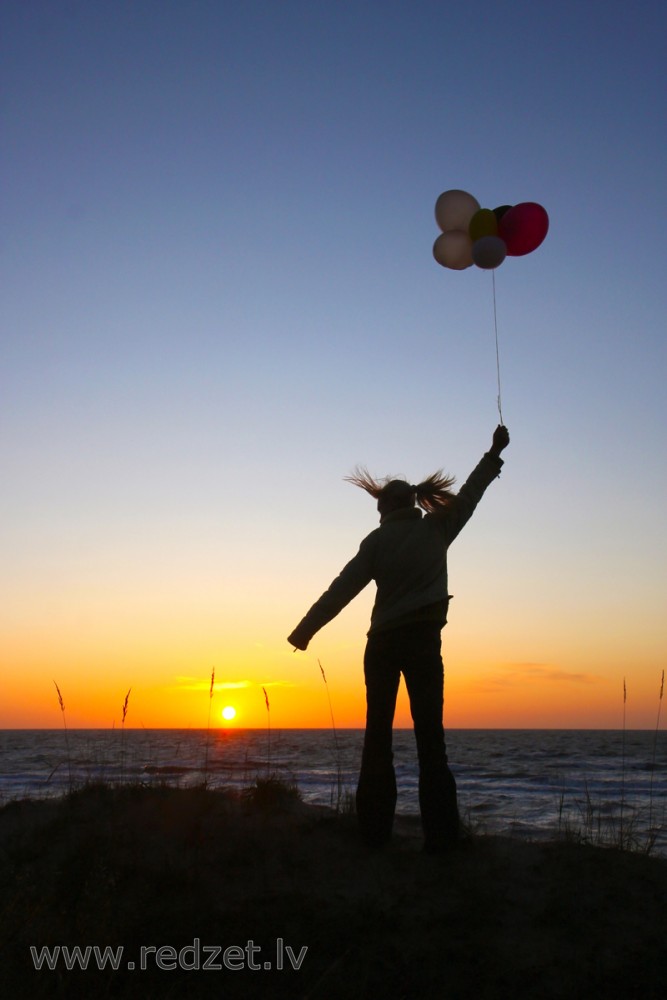 Meitene ar baloniem saulrietā