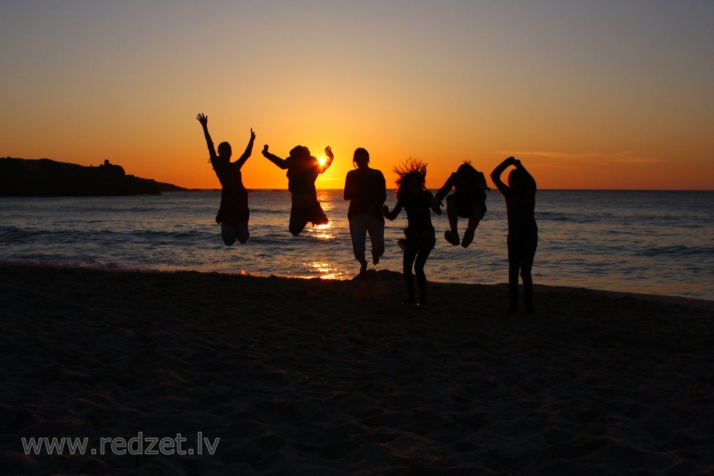 Group of People Jumping at Sunset
