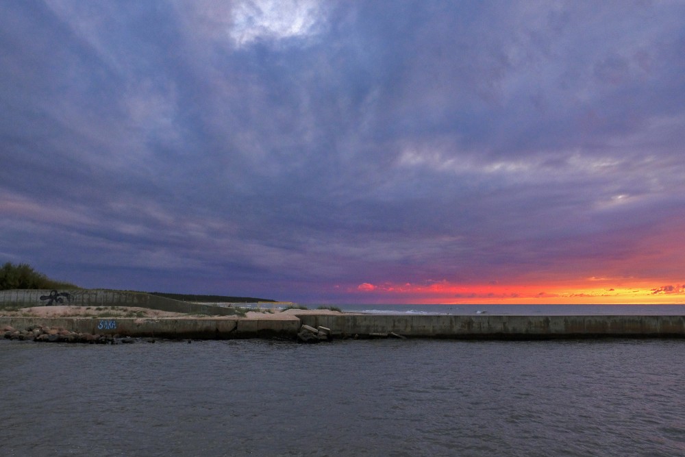 Concrete pier and fiery sunset over the sea in Pavilosta