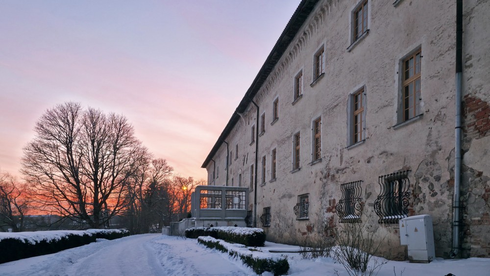 Dundaga Castle wall in winter twilight with snowy path and evening sky