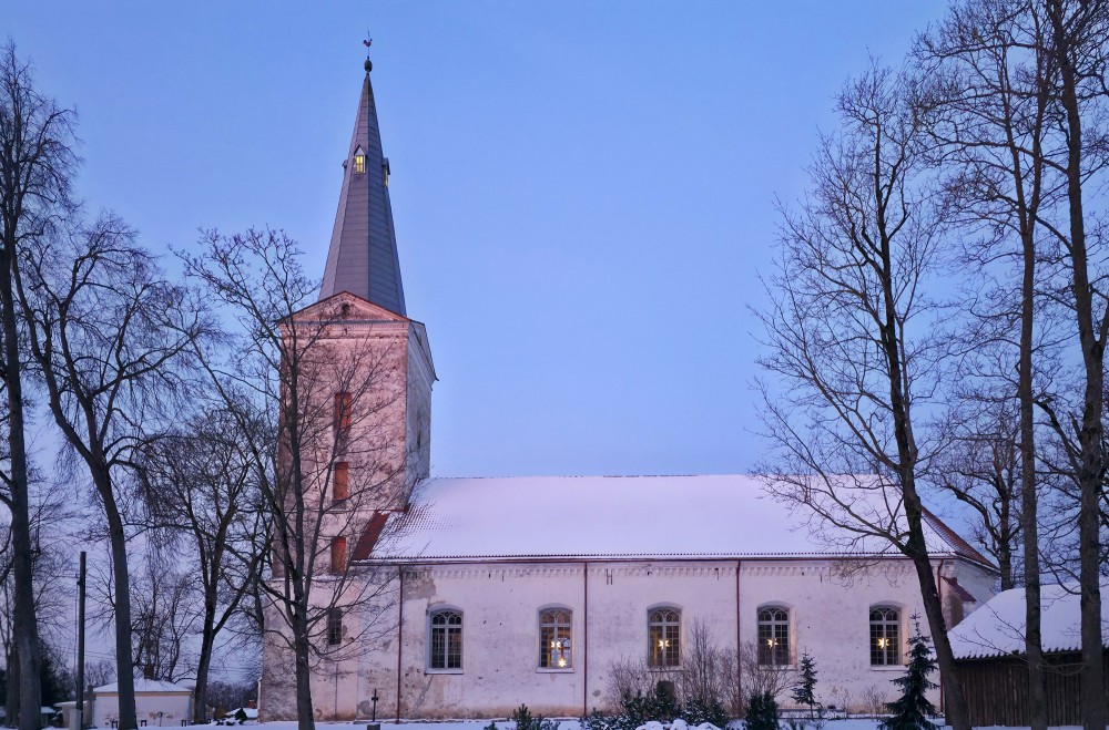 Dundagas luterāņu baznīca ziemā ar sniegotu jumtu un izgaismotiem logiem