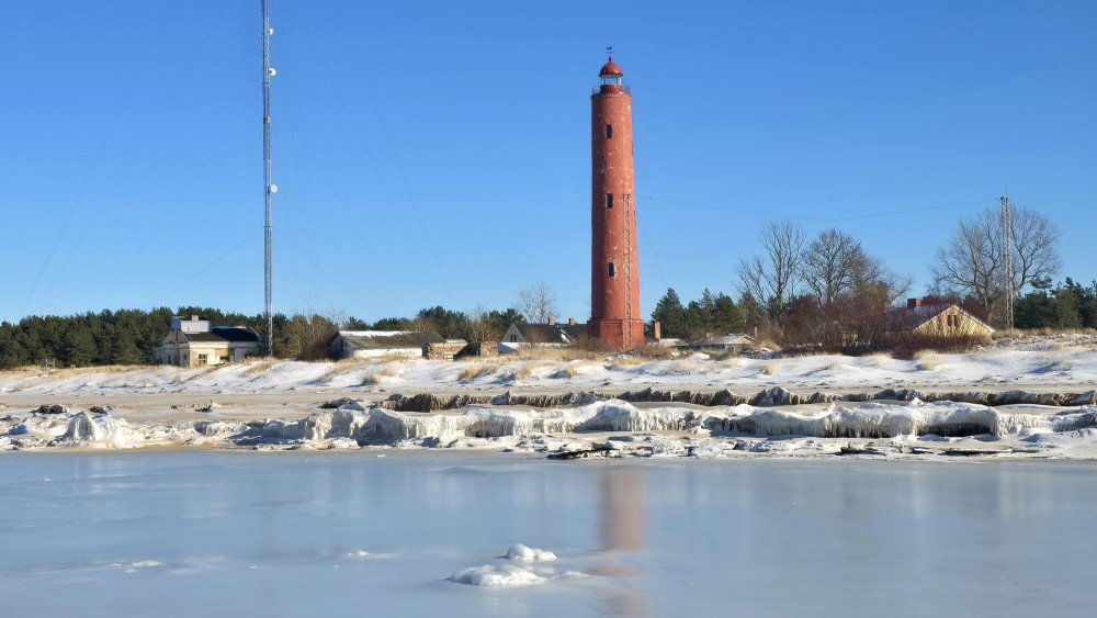 View of Akmensrags Lighthouse across a frozen beach