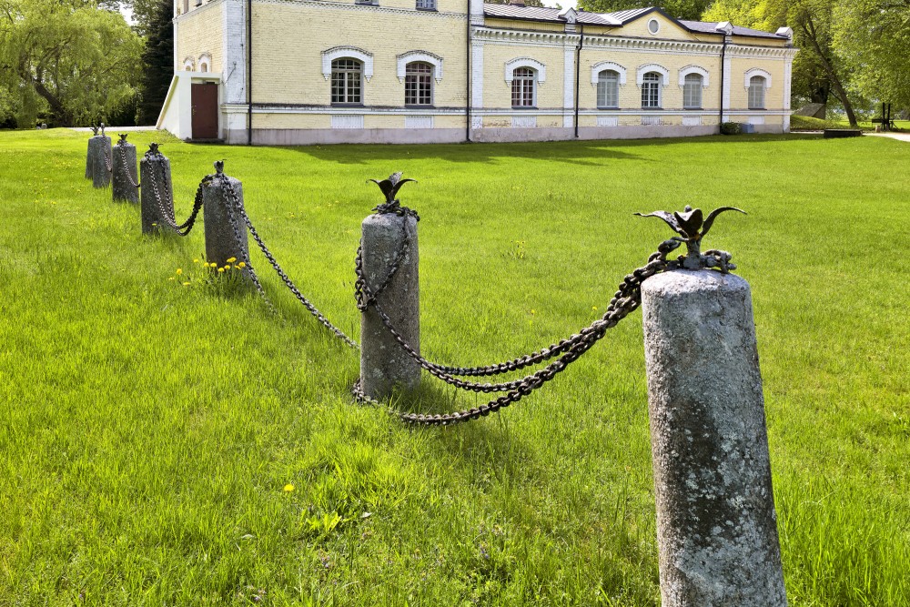 Historic stone posts with chains on the lawn of Dole Manor house