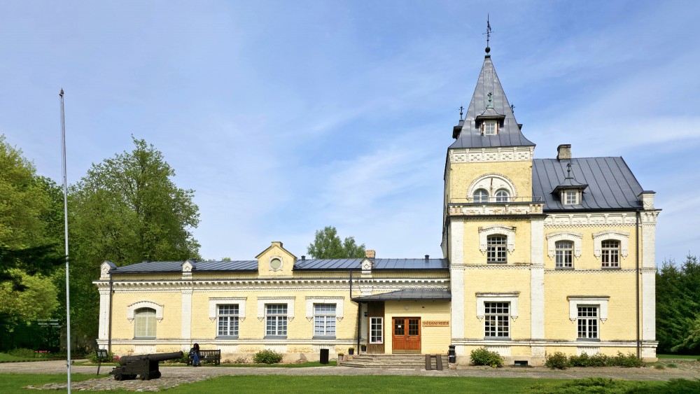 Central facade of Dole Manor house with a tower and historical cannon