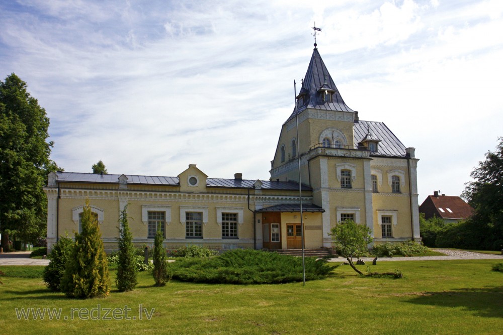 Main facade of the Dole Manor house with decorative conifers in the foreground