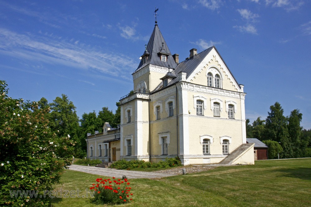 Facade of the Dole Manor house with a tower and blooming poppies in the foreground