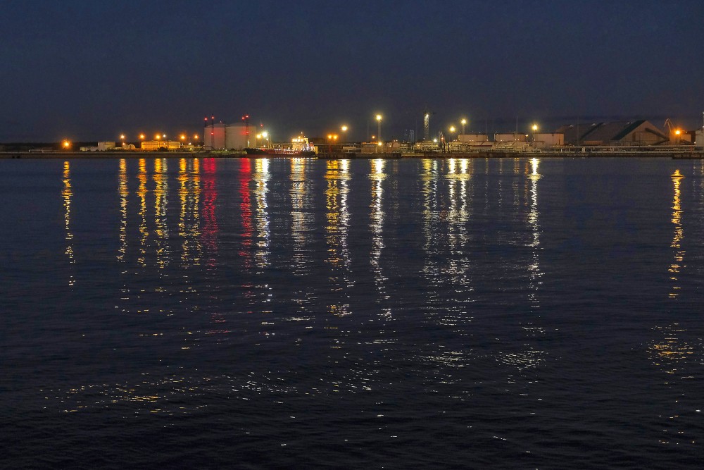 Illuminated shoreline of Ventspils port at dusk on the Venta River