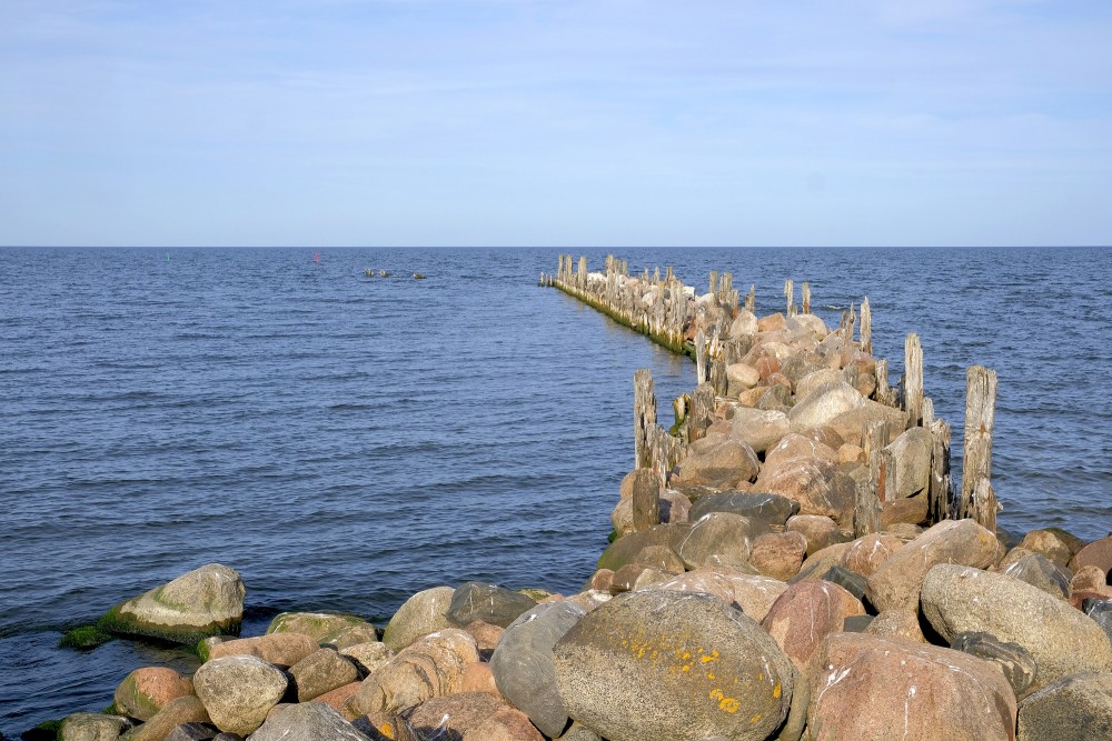Akmeņu mols, kas stiepjas jūrā zem skaidrām debesīm