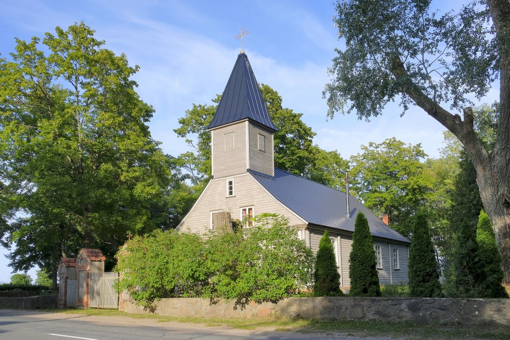Engures luterāņu baznīca sānskatā ar koka sienām un torni koku ieskautā ainavā