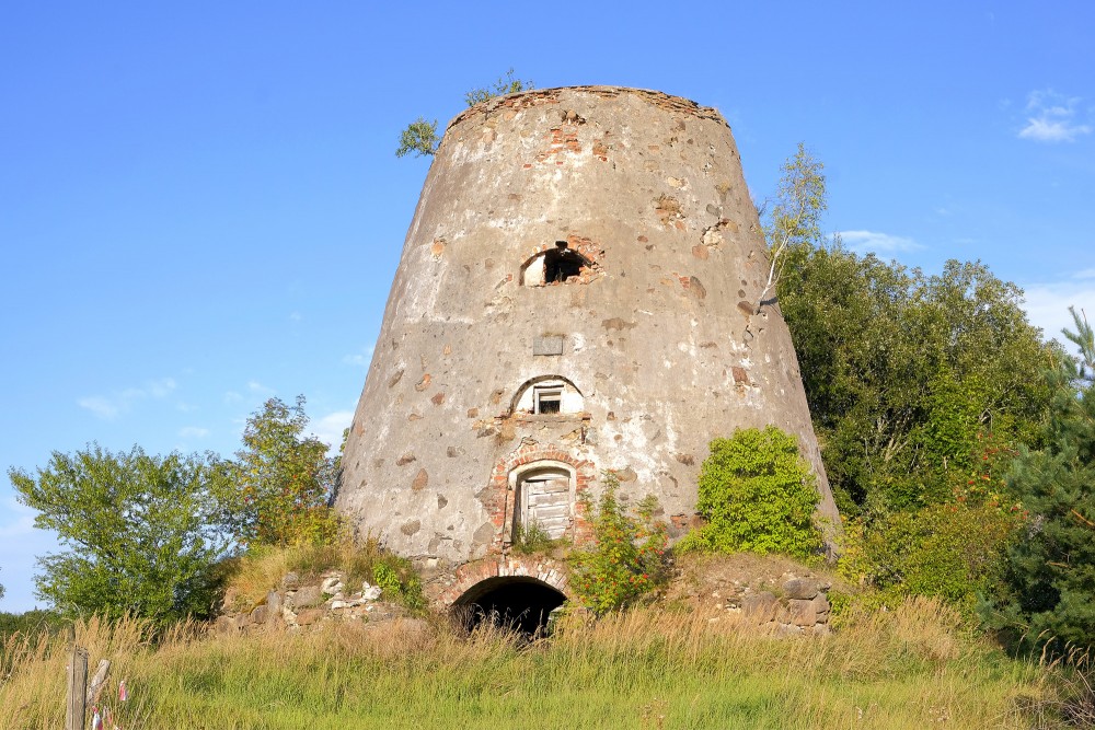 The ancient ruins of Minde windmill on a hill surrounded by green nature