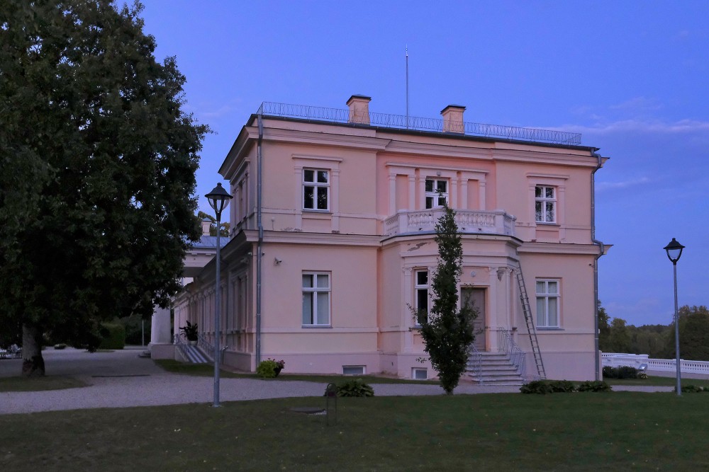 Renavas muižas kungu māja vakara gaismā ar balkonu un parka celiņu