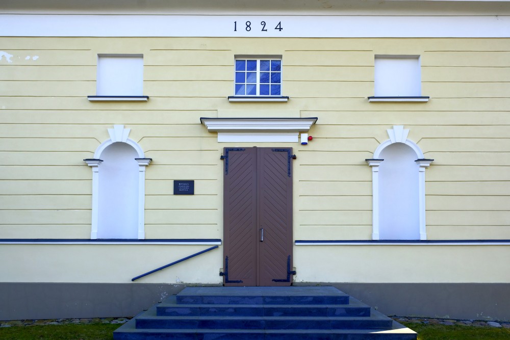Būtiņģes evaņģēliski luteriskās baznīcas ieeja ar kāpnēm un uzrakstu 1824