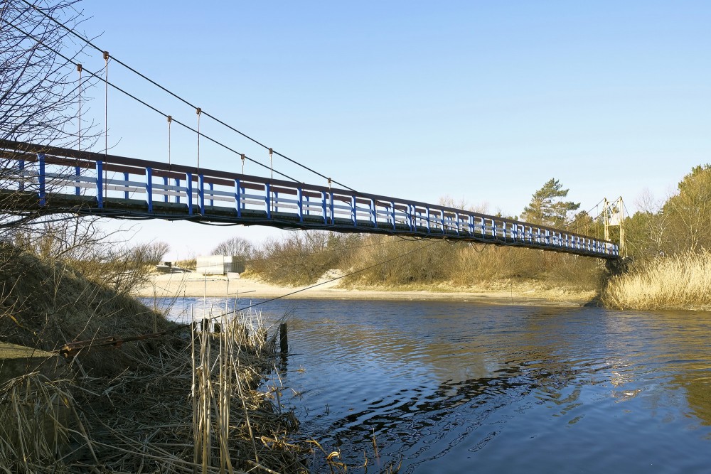 Sventājas Pērtiķu piekares tilts pāri upei plašā ainavā