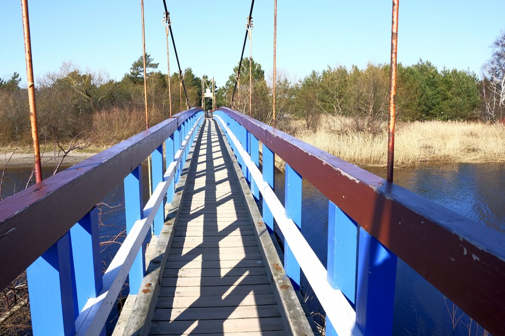 Skats pa Sventājas Pērtiķu tiltu ar zilām margām virs upes