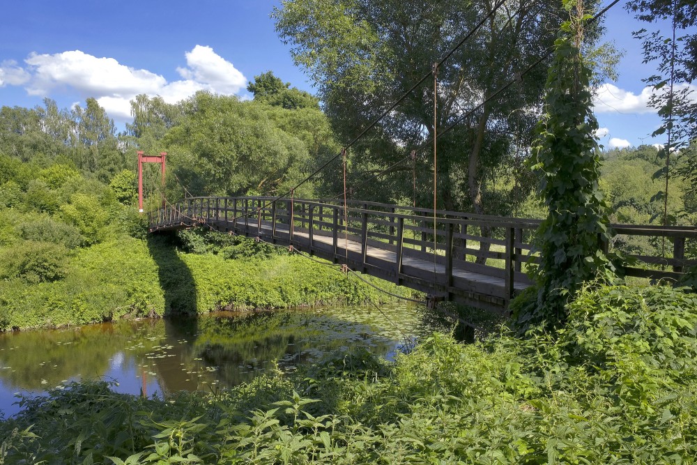 Wooden suspension bridge over Akmena river in green nature landscape Wooden suspension bridge over Akmena river in green nature landscape