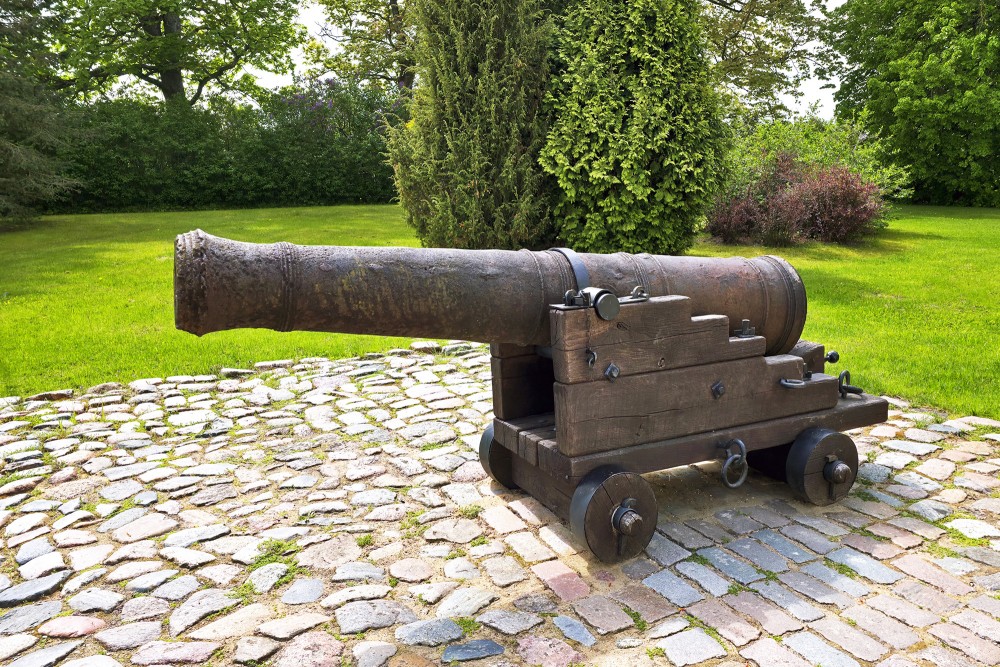 Ancient cannon on a cobblestone area in the Daugava Museum park on Dole Island