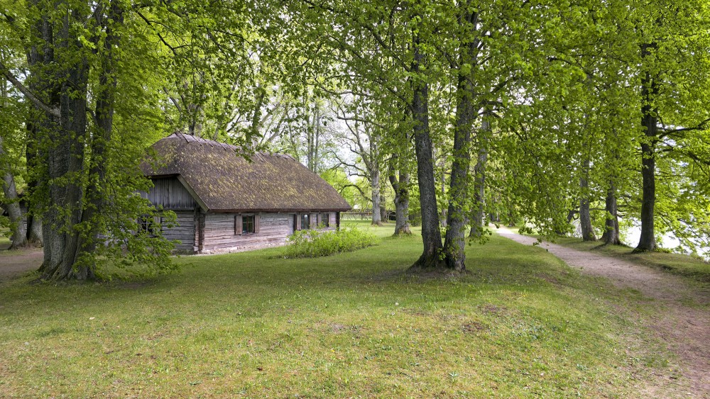 Ancient wooden residential house among lush trees in the territory of the Daugava Museum