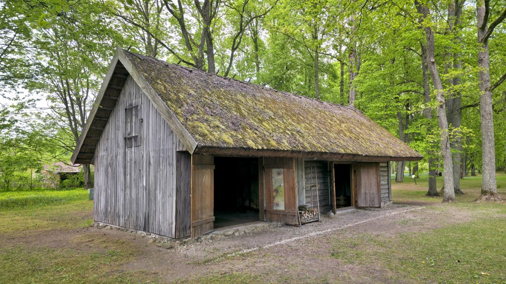 Ancient wooden barn with a mossy thatched roof at the Daugava Museum