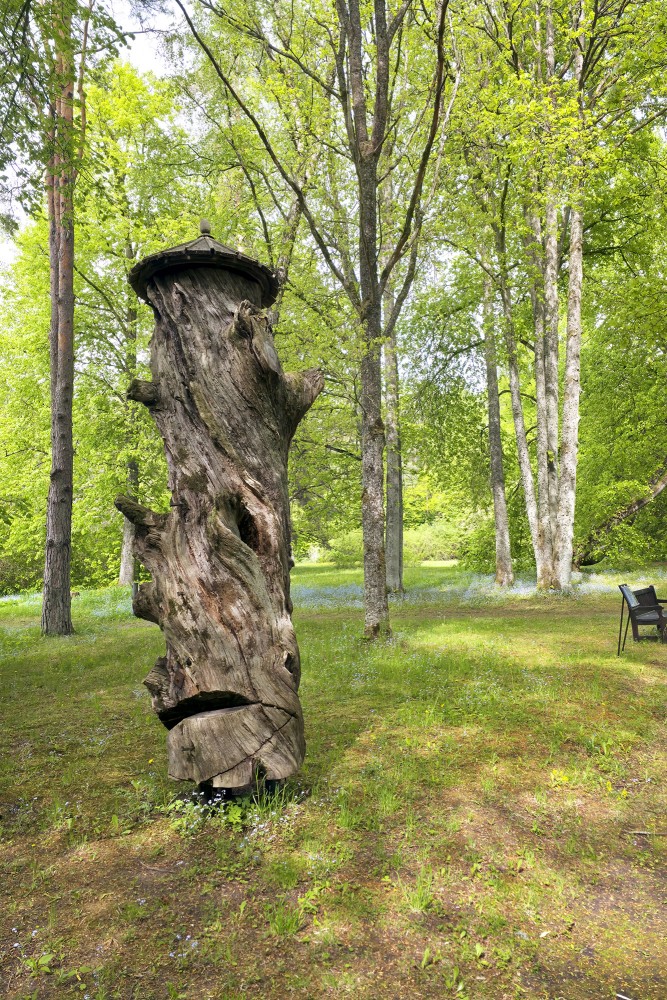 Historical hollow tree hive trunk with a small roof at the Daugava Museum open-air exhibition