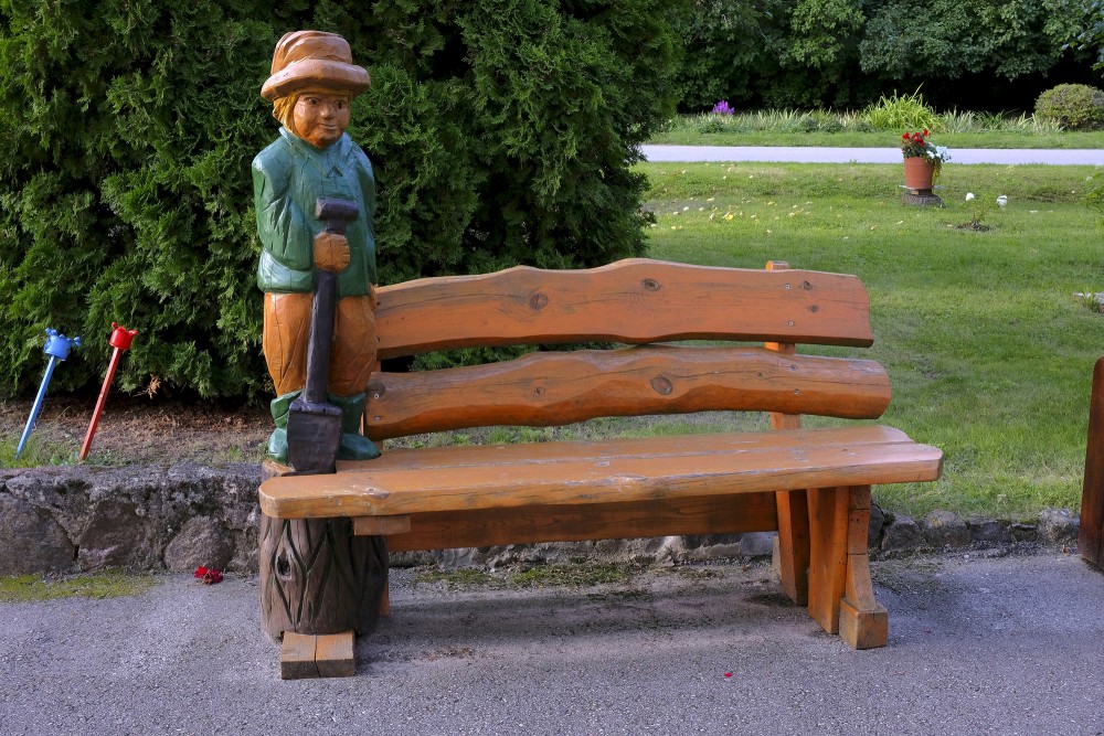 A wooden bench with a sculpture in the village of Ezere