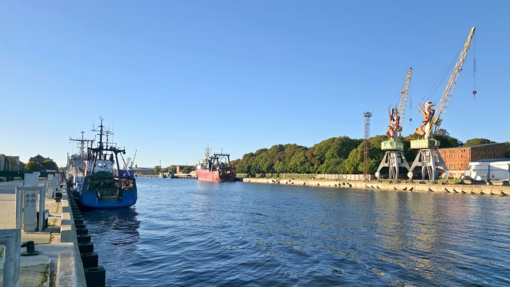 Liepaja trade canal with fishing vessels and harbor cranes