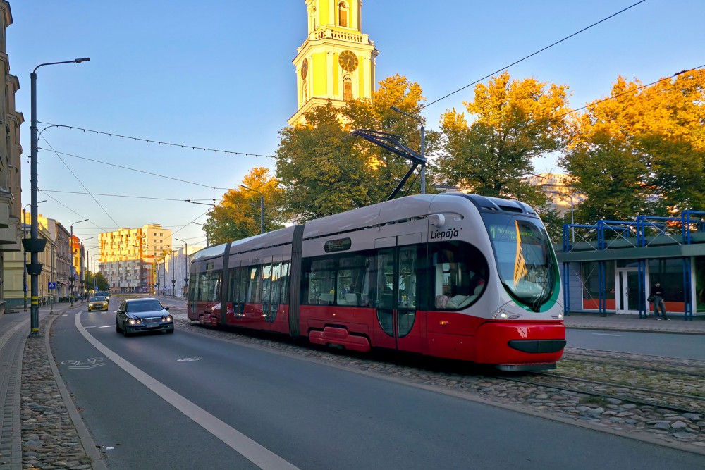 Sarkans tramvajs brauc gar Liepājas Svētās Trīsvienības katedrāli