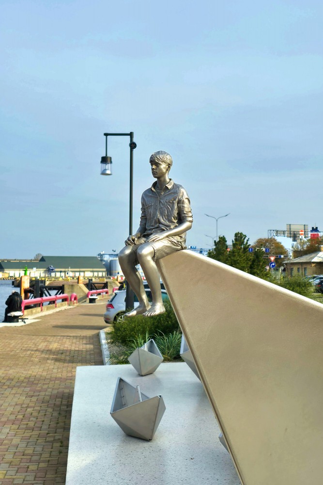 Boy figure on steel boat bow on Ventspils port promenade