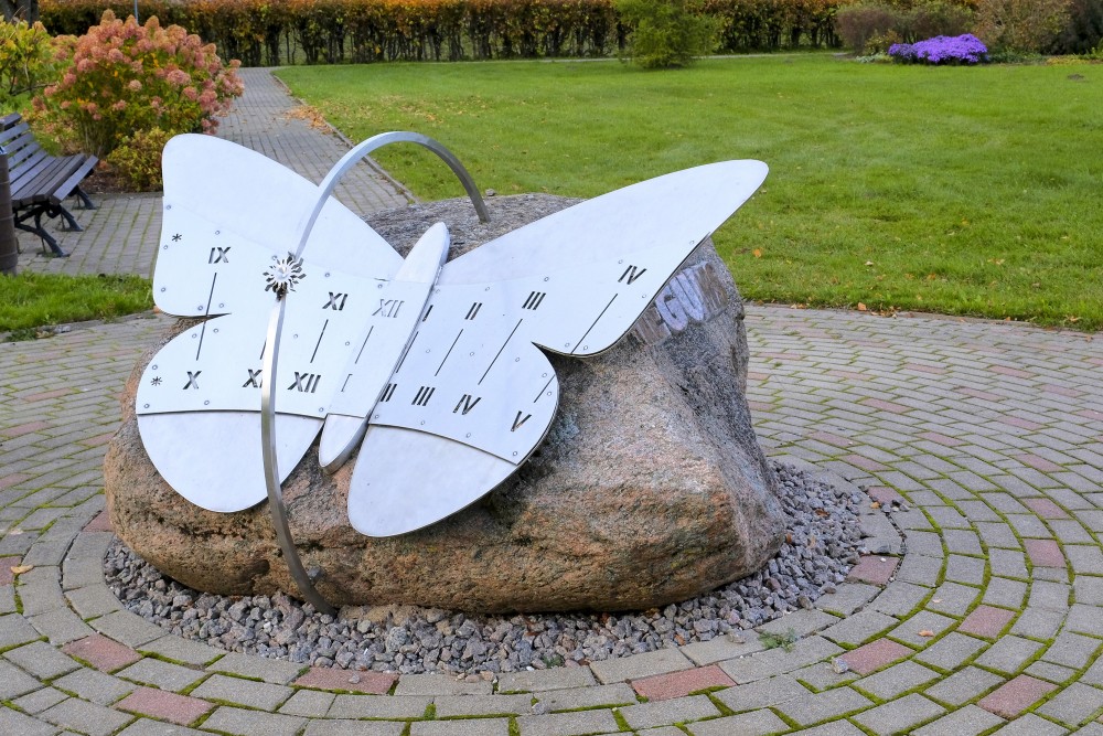 Environmental sundial sculpture on stone base in a park